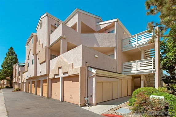 Front view of a multi-story apartment building with balconies and garages.