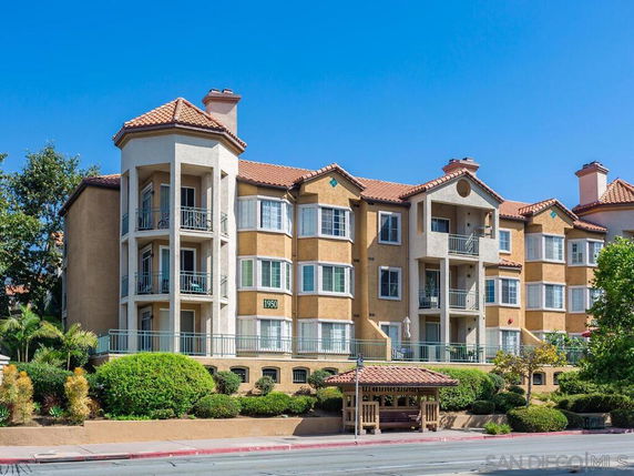 Front view of a multi-story residential building with balconies and tiled roofs.