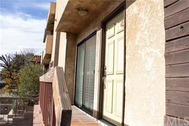 Exterior view of a building with a wooden railing and a door with a screen.