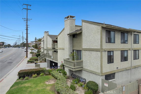 Front view of a multi-story residential building with balconies and a sloped roof.
