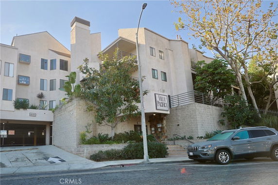 Front view of a multi-story residential building with balconies and a gated entrance.