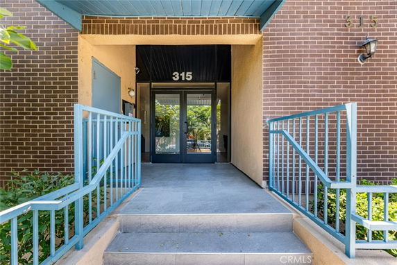 Front view of a building entrance with blue railings and glass doors.