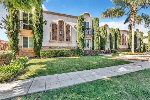 Front view of a two-story house with large arched windows and decorative stonework.