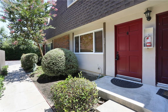 Front view of a two-story building with red doors and a window on the first floor.