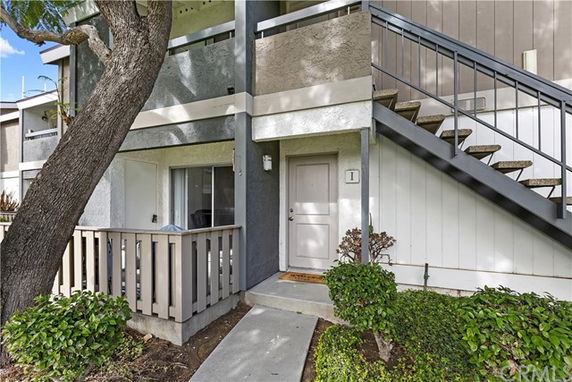 Front view of a two-story residential building with a small porch and exterior staircase.