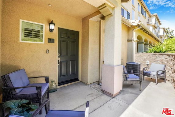 Front view of a house entrance with seating area on a small porch.