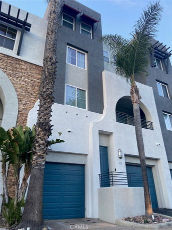 Front view of a multi-story building with blue garage doors and archway entrance.