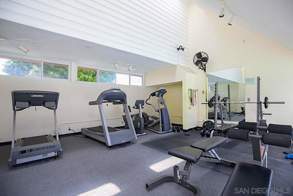 Indoor gym area with exercise equipment including treadmills and weightlifting benches.