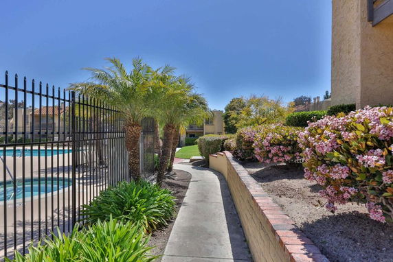 Outdoor area with a fenced swimming pool and surrounding walkway.
