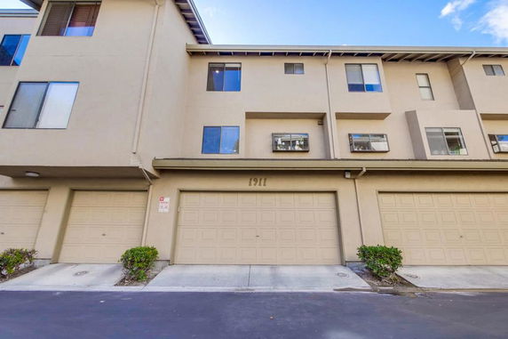 Front view of a multi-story townhouse with garage doors.