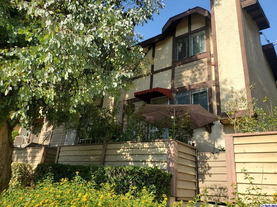 Front view of a two-story house with a wooden fence and large windows.