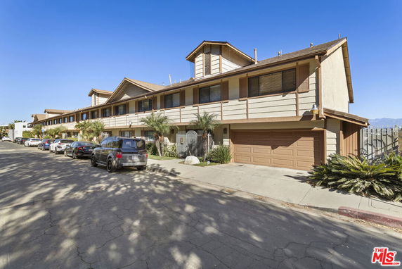 Front view of a two-story building with garages and parked cars along the street.