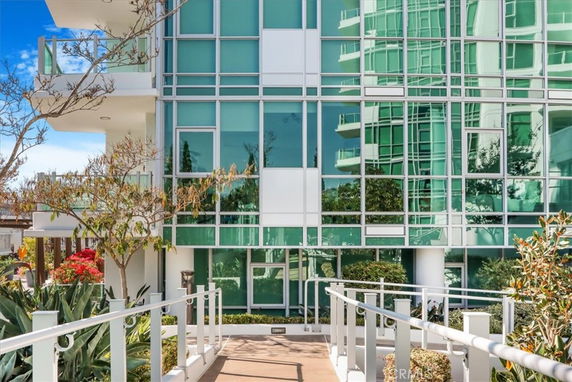 Front view of a modern glass-faced building with a walkway leading to it.