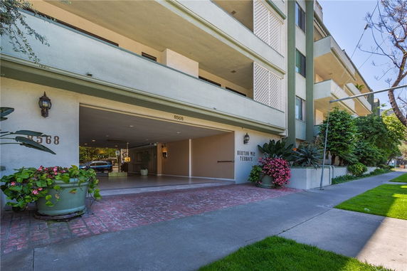 Front view of a multi-story apartment building with a covered entrance.