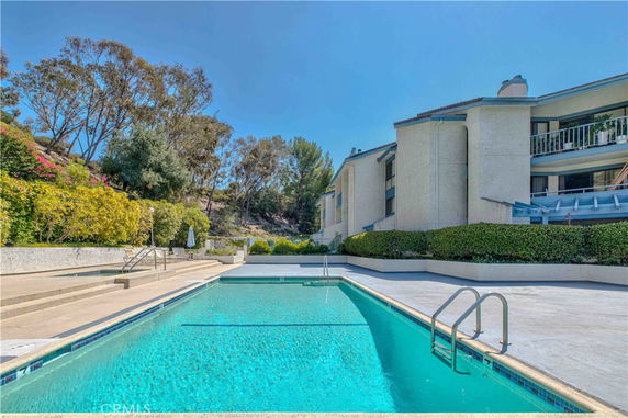 Outdoor swimming pool beside a multi-story building.