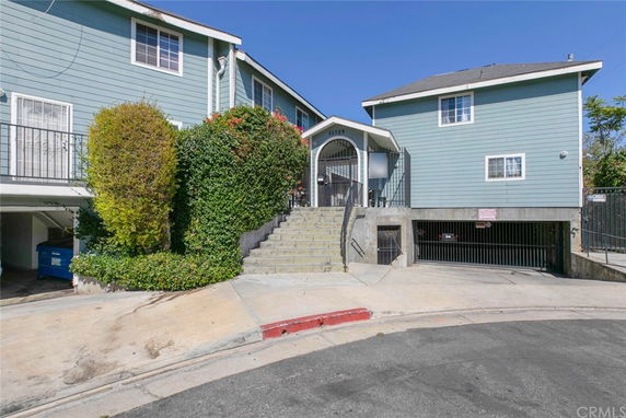 Front view of a multi-story house with stairs leading to the entrance.