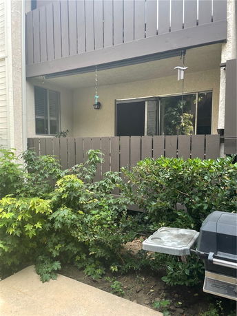 View of a building with a fenced balcony and plants in front.