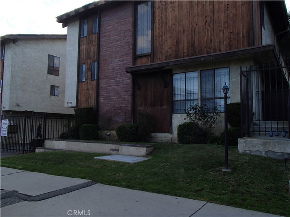 Front view of a multi-story building with brick and wood facade.