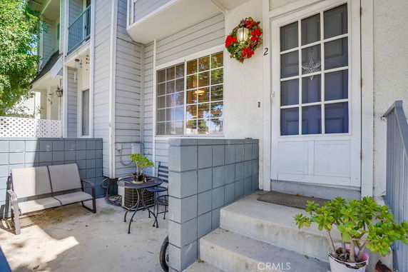 Front view of a house entrance with a small patio area and seating.