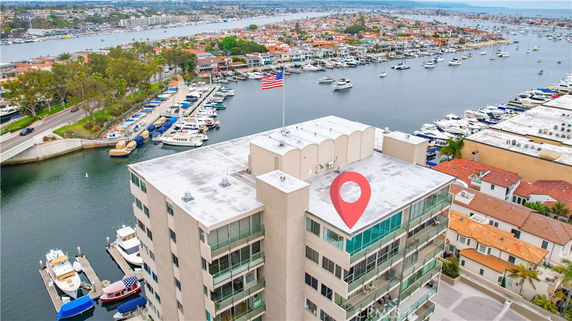 Aerial view of waterfront buildings with boats and a marina in the background.