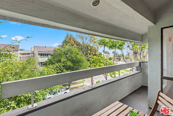 View from a balcony overlooking nearby buildings and greenery.
