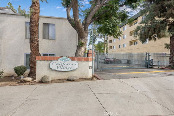 Front view of a multi-story residential building complex with a gated entrance and signage.