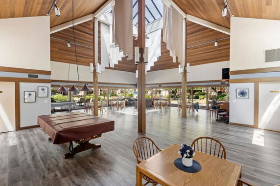 Interior view of a clubhouse with a billiards table and dining area.