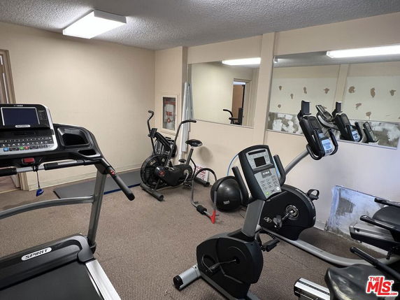 Room with gym equipment including treadmills and exercise bikes.