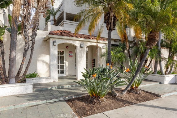 Front view of a building with white stucco walls and a tiled roof entrance.