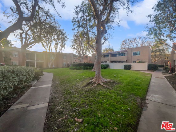 Front view of residential buildings with a landscaped pathway and trees.