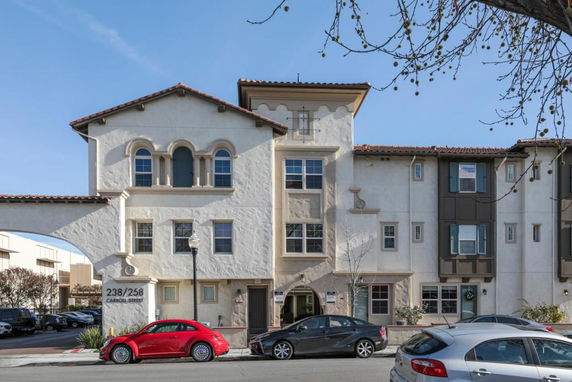 Front view of a multi-story residential building with arched windows and a garage door at the ground level.