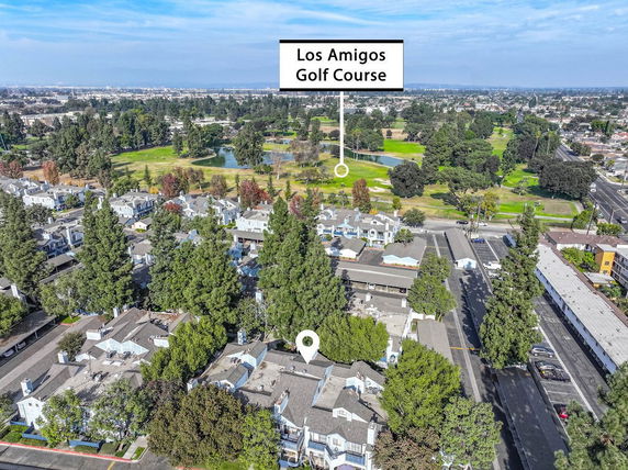 Aerial view of a residential neighborhood with adjacent golf course, trees, and surrounding landscape.