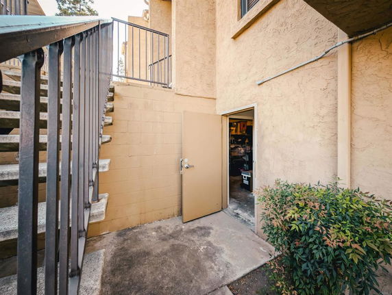 Outdoor view of a building with a stairway and an open storage room door.