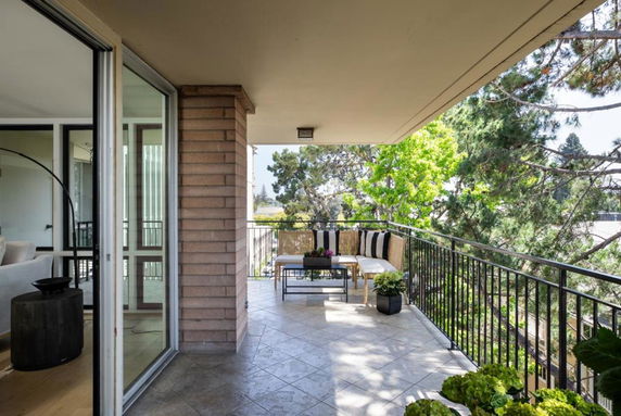 Balcony view showing seating area and partial surrounding landscape.