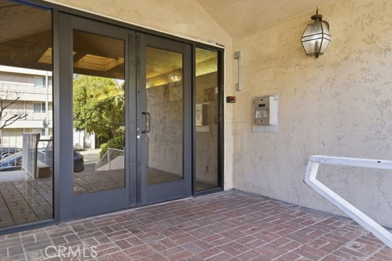 Entrance view of a building with double glass doors and a brick walkway.