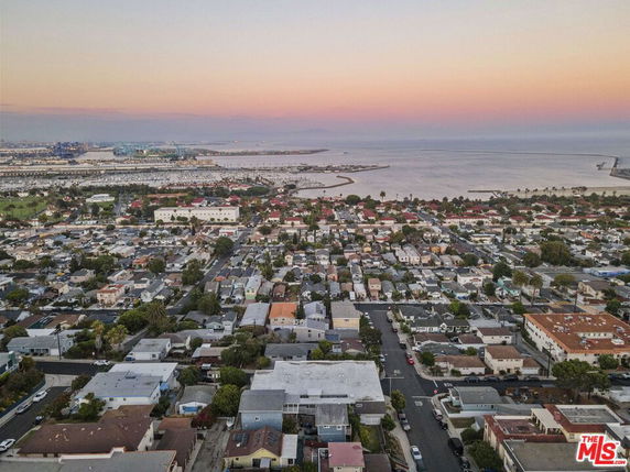 Wide view of a suburban area with a coastal background and sunset sky.