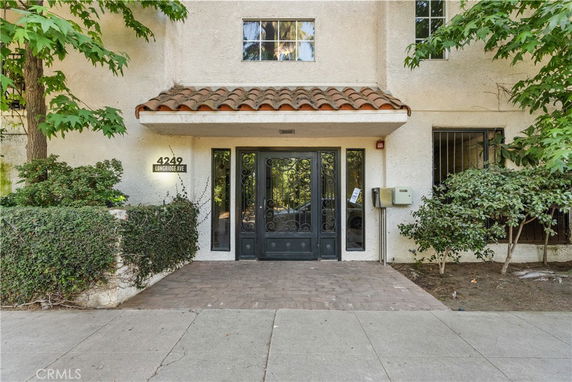 Front view of a building entrance with decorative black doors and a tiled canopy.
