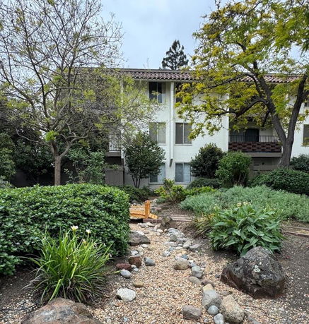 Front view of a multi-story building with a landscaped garden.
