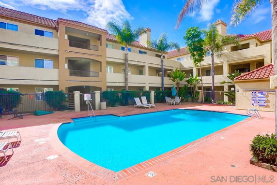 Outdoor swimming pool area surrounded by a multi-story residential building.
