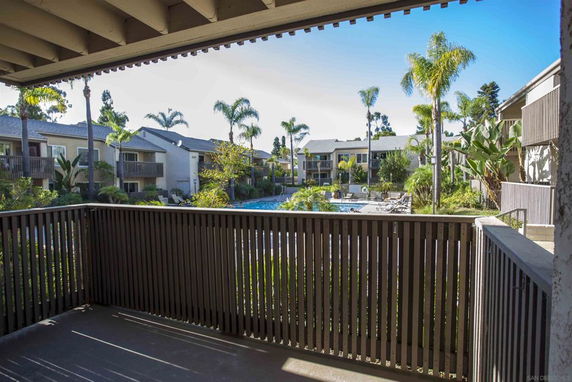 View of apartment complex with swimming pool and palm trees.