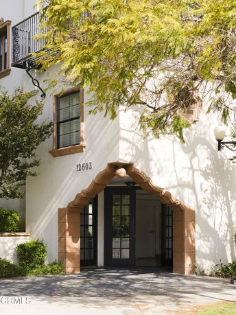 Front view of a building entrance with arched doorway and balcony above.