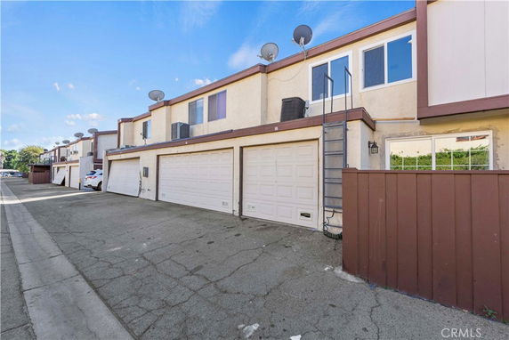 Front view of a two-story residential building with garages and satellite dishes.