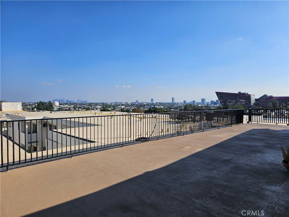 Panoramic view of a cityscape from a rooftop with a railing.