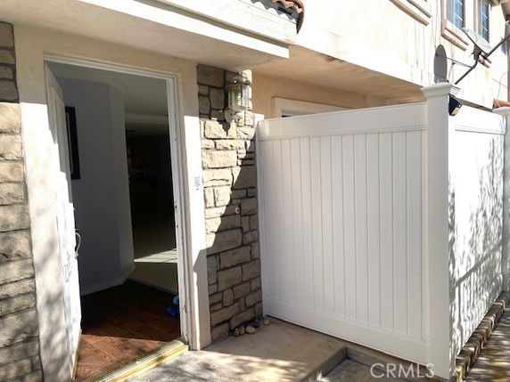 Front view of a house entrance with an open door and white privacy fence.