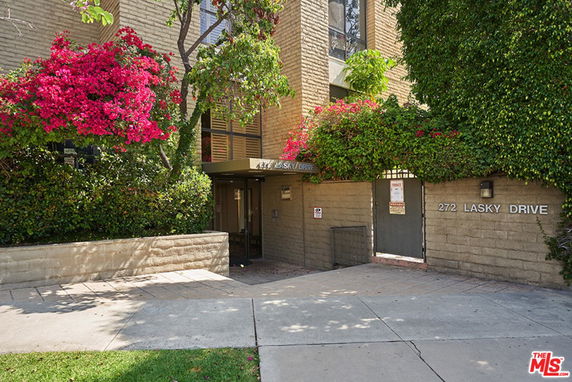 Front view of a building entrance with plants and flowers.