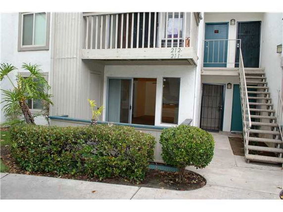 Front view of an apartment building with stairs and a balcony.