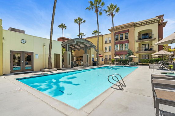 Outdoor swimming pool area in front of a multi-story building.