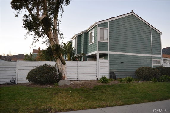 Front view of a two-story house with a white fence.