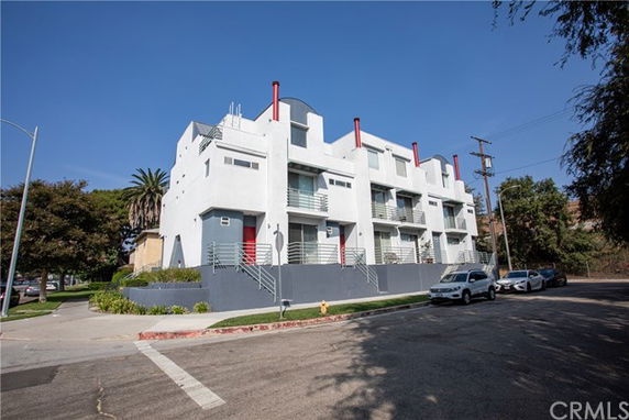 Front view of a modern multi-story building with balconies and red vertical elements.