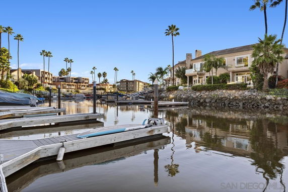 Panoramic view of waterfront residential buildings with docks and palm trees.